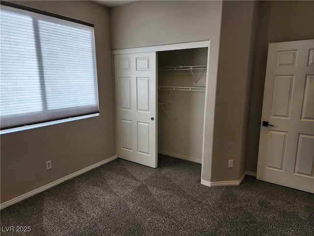 unfurnished bedroom with a closet, multiple windows, and dark colored carpet