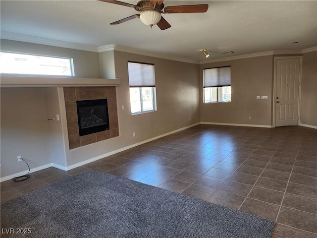 unfurnished living room with a tiled fireplace, ceiling fan, a healthy amount of sunlight, and crown molding