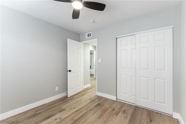 unfurnished bedroom featuring ceiling fan, a closet, and light wood-type flooring