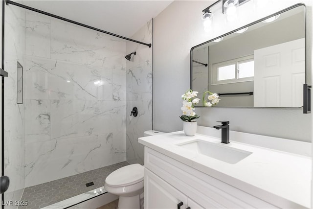 bathroom featuring a tile shower, vanity, and toilet