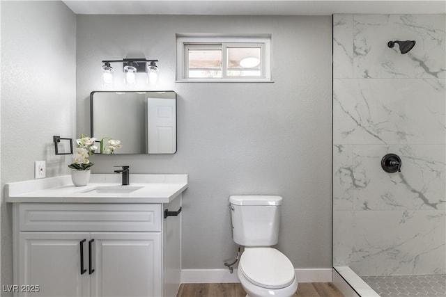 bathroom featuring tiled shower, vanity, hardwood / wood-style flooring, and toilet