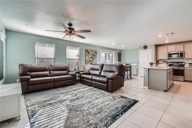 tiled living room featuring a textured ceiling, ceiling fan, and sink