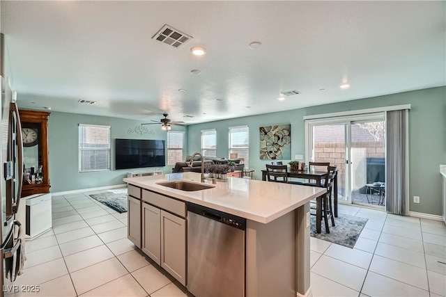 kitchen with ceiling fan, dishwasher, sink, light tile patterned flooring, and an island with sink