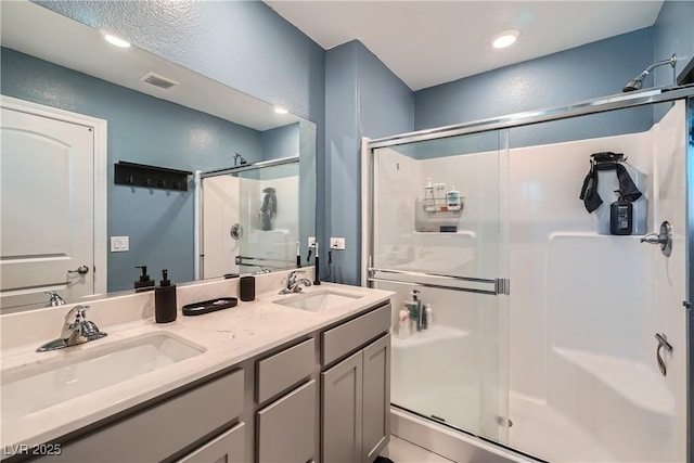 bathroom featuring a shower with shower door and vanity