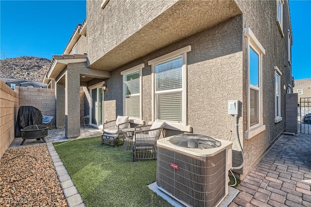 exterior space featuring an outdoor living space with a fire pit, a yard, a patio, and central air condition unit