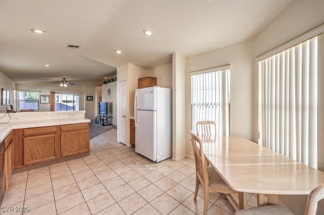 kitchen with ceiling fan, tile counters, white fridge, and light tile patterned floors