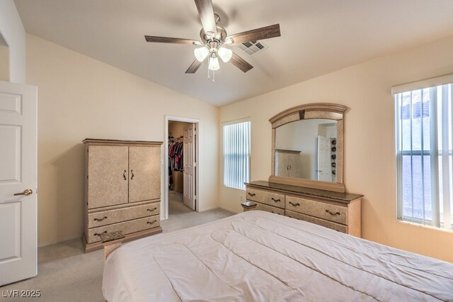 bedroom with lofted ceiling, light carpet, a walk in closet, ceiling fan, and a closet