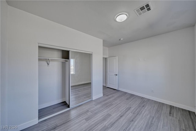 unfurnished bedroom with light wood-type flooring and a closet