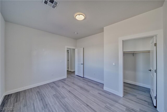 unfurnished bedroom with a closet and light hardwood / wood-style floors