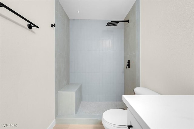 bathroom featuring vanity, toilet, and a tile shower