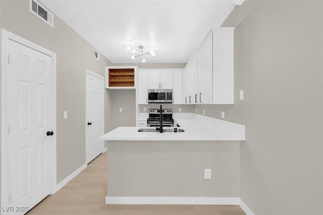 kitchen featuring kitchen peninsula, appliances with stainless steel finishes, light hardwood / wood-style floors, and white cabinetry