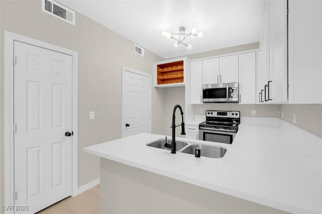 kitchen with kitchen peninsula, stainless steel appliances, sink, white cabinets, and a chandelier