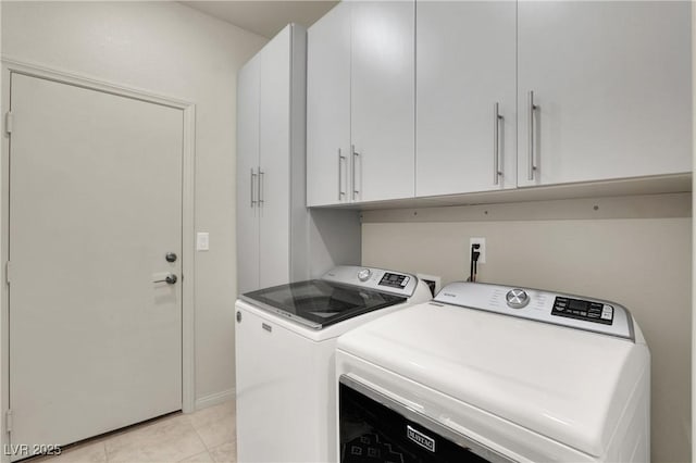 laundry area with washing machine and dryer, light tile patterned floors, and cabinets