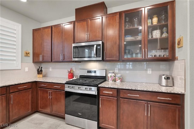 kitchen with light stone counters, appliances with stainless steel finishes, and decorative backsplash