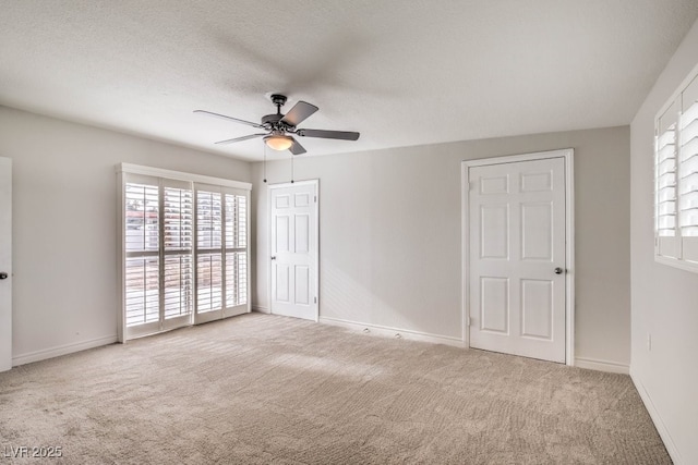 unfurnished room featuring ceiling fan, light colored carpet, and a textured ceiling