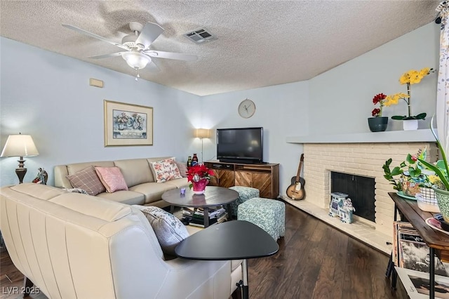 living room with a fireplace, a textured ceiling, ceiling fan, and dark wood-type flooring