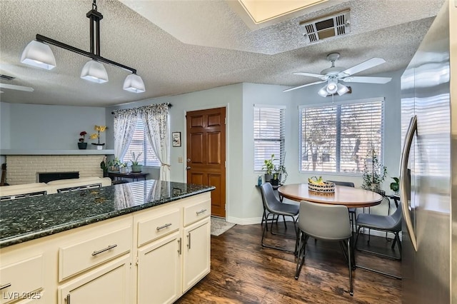 kitchen with stainless steel refrigerator, a wealth of natural light, dark wood-type flooring, and decorative light fixtures