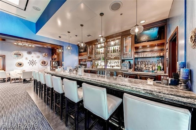 bar with pendant lighting and dark stone countertops