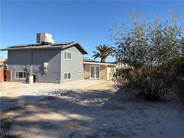 back of property with central air condition unit, a patio area, french doors, and solar panels