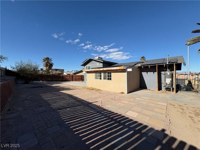 rear view of house featuring solar panels, a patio area, and water heater