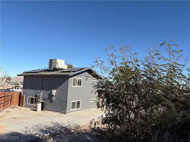 rear view of house with central AC unit, solar panels, and a patio area