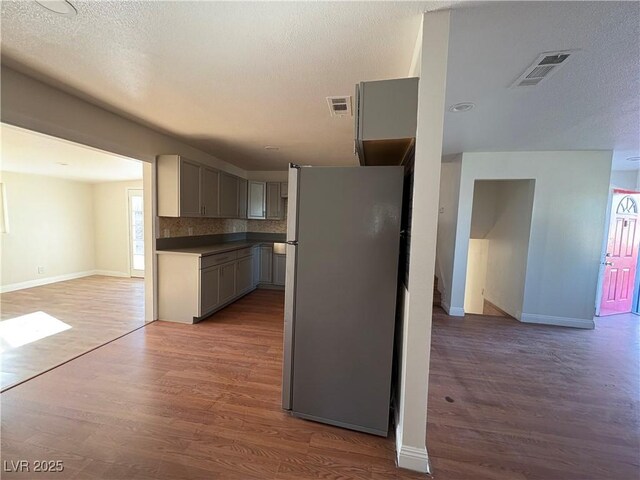 kitchen with gray cabinets, stainless steel fridge, dark hardwood / wood-style flooring, and tasteful backsplash