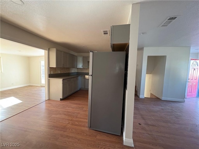 kitchen featuring stainless steel refrigerator, backsplash, dark hardwood / wood-style floors, and gray cabinetry