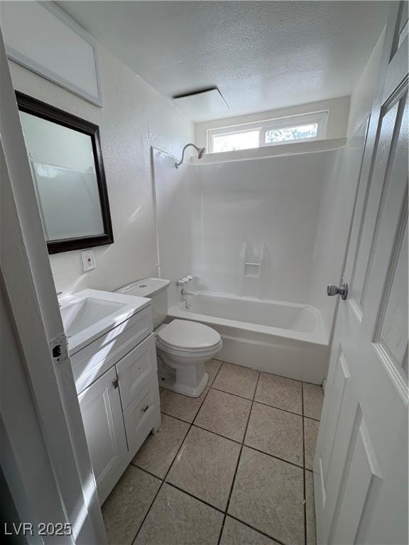 full bathroom with toilet, vanity, a textured ceiling, tile patterned flooring, and washtub / shower combination