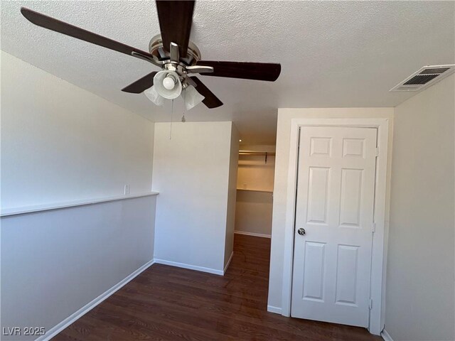 interior space featuring ceiling fan, a textured ceiling, and dark wood-type flooring