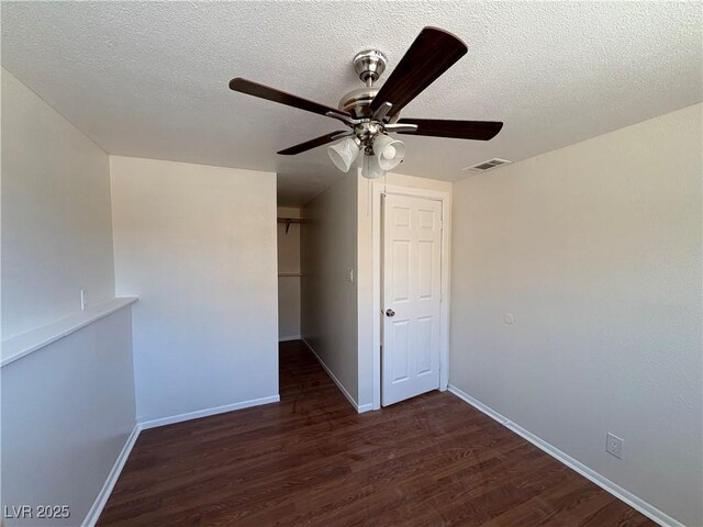 empty room with a textured ceiling, ceiling fan, and dark wood-type flooring