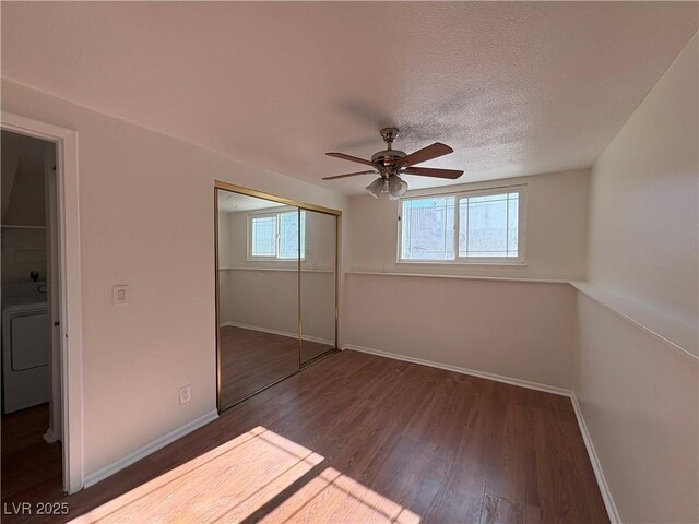 unfurnished bedroom featuring ceiling fan, dark hardwood / wood-style floors, washer / clothes dryer, a textured ceiling, and a closet