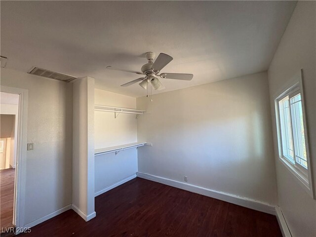 empty room featuring ceiling fan, dark hardwood / wood-style floors, and a baseboard heating unit