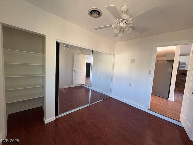 unfurnished bedroom featuring dark wood-type flooring, ceiling fan, and a closet