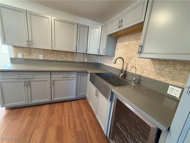 kitchen with gray cabinetry, tasteful backsplash, sink, and light hardwood / wood-style flooring