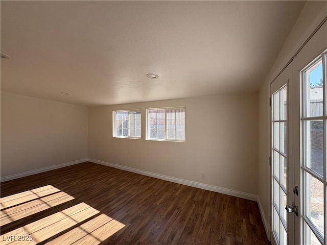 spare room featuring dark hardwood / wood-style floors, a wealth of natural light, and french doors