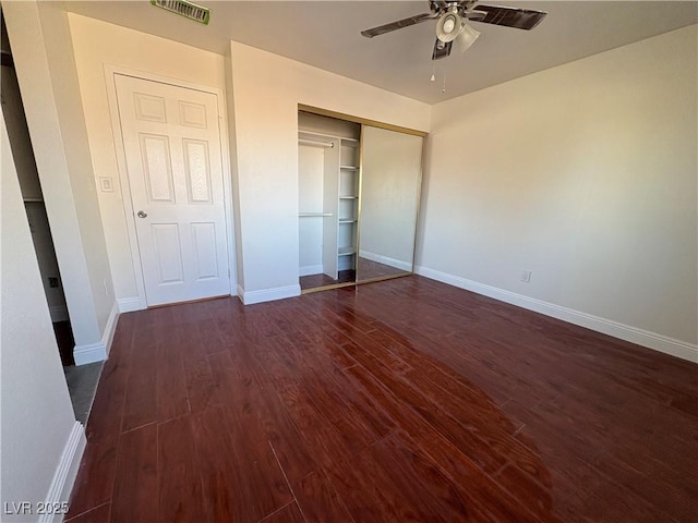 unfurnished bedroom with ceiling fan, dark hardwood / wood-style flooring, and a closet