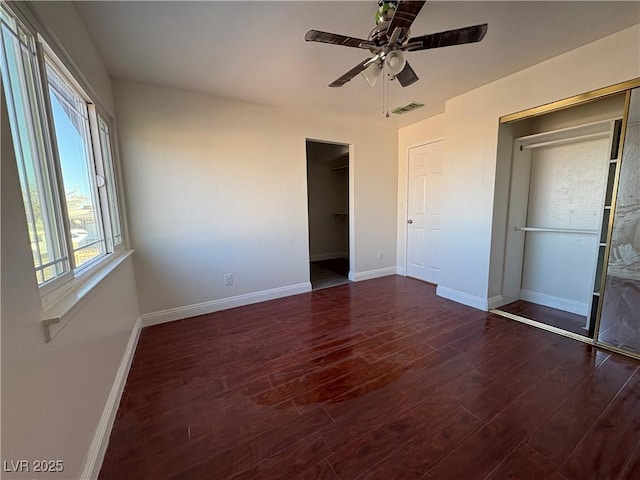 unfurnished bedroom featuring dark hardwood / wood-style flooring, a spacious closet, a closet, and ceiling fan