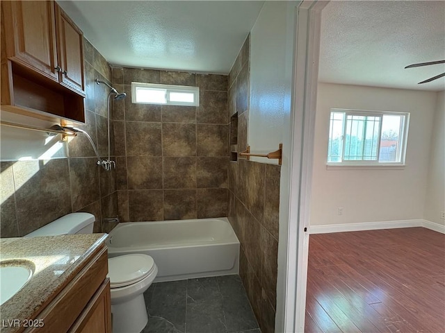 full bathroom featuring tiled shower / bath, a textured ceiling, toilet, vanity, and hardwood / wood-style flooring