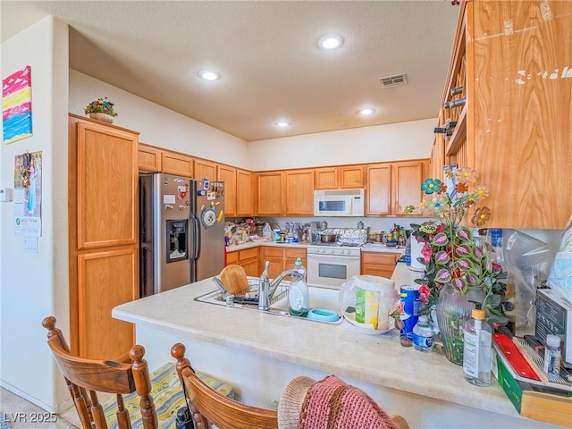 kitchen with a kitchen bar, kitchen peninsula, light tile patterned floors, and white appliances