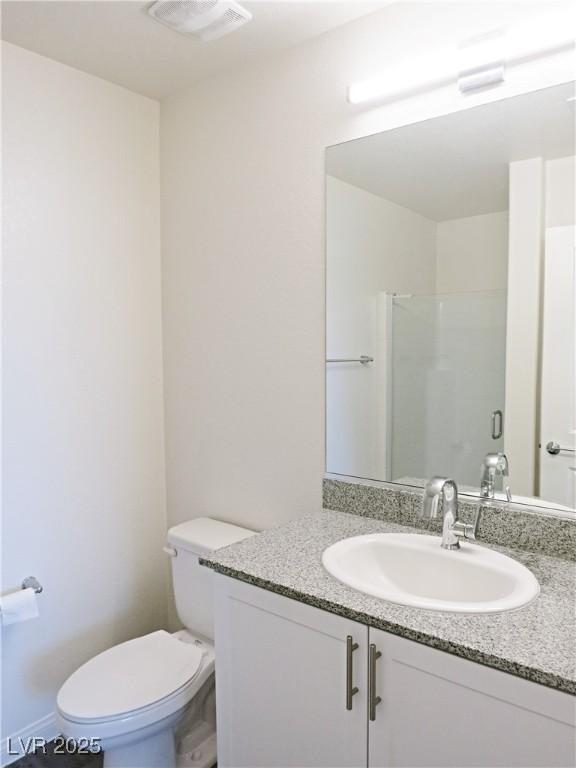 bathroom with walk in shower, vanity, and toilet