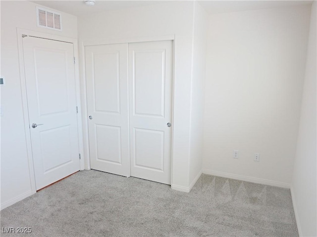 unfurnished bedroom featuring light colored carpet and a closet