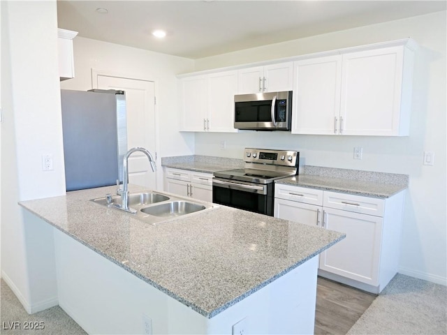 kitchen featuring white cabinets, stainless steel appliances, light stone counters, and sink