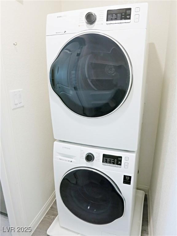 washroom featuring stacked washer and dryer and light hardwood / wood-style flooring