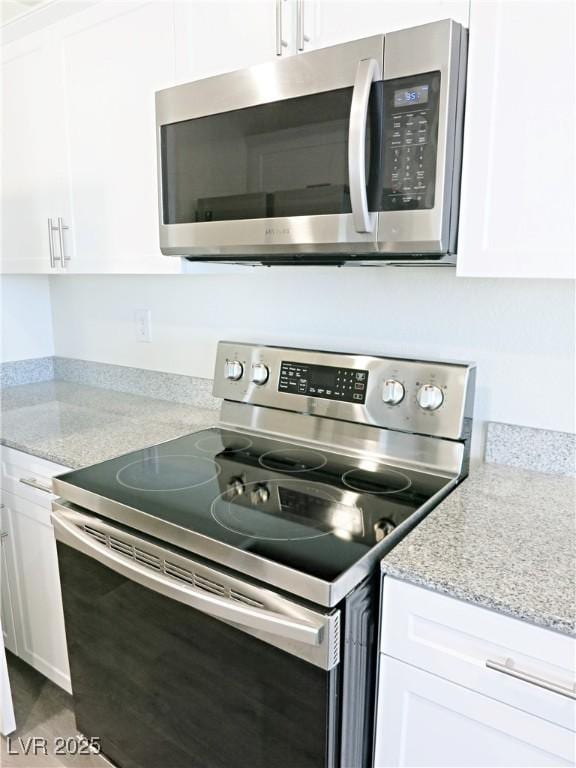 kitchen with light stone countertops, white cabinetry, and stainless steel appliances