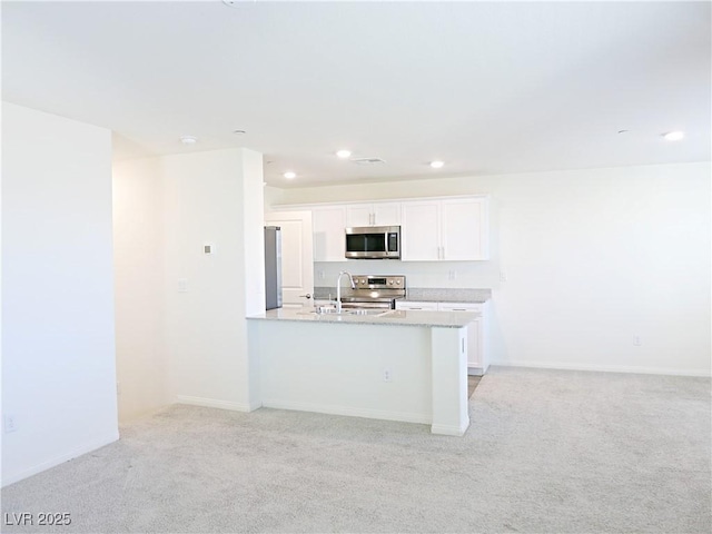 kitchen with white cabinetry, sink, stainless steel appliances, an island with sink, and light carpet