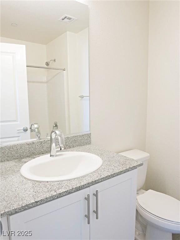 bathroom with vanity, toilet, and a shower