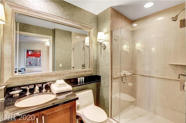 bathroom featuring vanity, toilet, and a shower with door