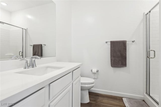 bathroom with hardwood / wood-style floors, vanity, a shower with door, and toilet