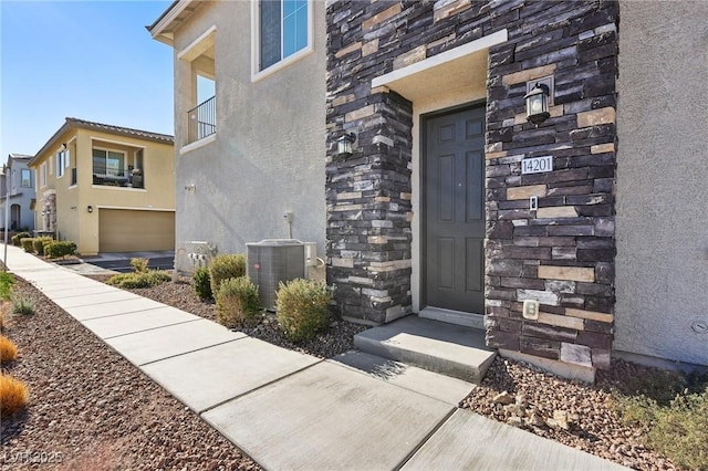 view of exterior entry featuring a garage and cooling unit