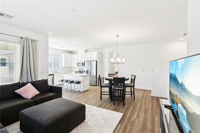 living room with a chandelier, light hardwood / wood-style flooring, and sink